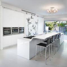 a modern kitchen with white cabinets and black bar stools