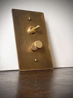 a light switch with two knobs on the side of it and a white wall in the background