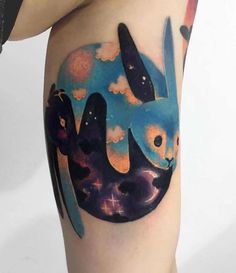 a woman's thigh with an abstract rabbit tattoo on it, and clouds in the background