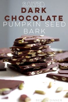 salted dark chocolate pumpkin seed bark is stacked on top of each other with the words, salted dark chocolate pumpkin seed bark