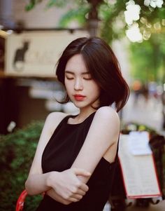 a woman in black dress standing next to a lamp post