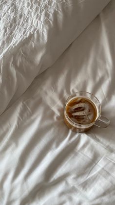 a cup of coffee sitting on top of a bed