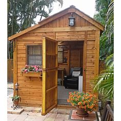 a small wooden shed sitting on top of a brick patio next to a potted plant