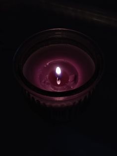 a lit candle sitting in the dark on top of a table