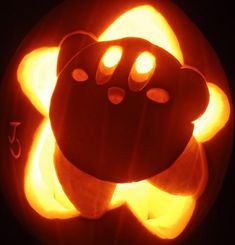 a pumpkin carved to look like a bear with glowing eyes and paws on it's face