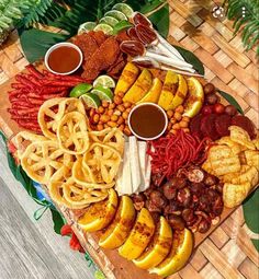 a platter filled with different types of food on top of a wooden table next to green leaves