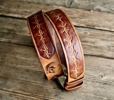 two brown leather bracelets sitting on top of a wooden table