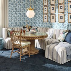 a living room with blue and white wallpaper has a round table surrounded by striped couches