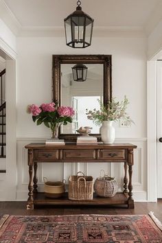 a hallway with a table, mirror and flowers on it