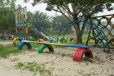 colorful playground equipment in the middle of a park with grass and dirt on the ground