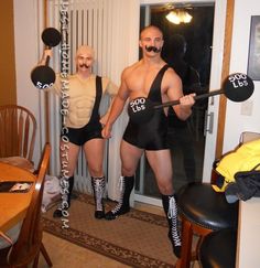 two men dressed up in wrestling gear posing for the camera with their arms around each other