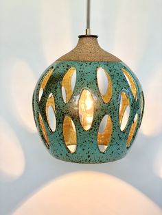 a green and gold colored light fixture hanging from a ceiling lamp with circles on it