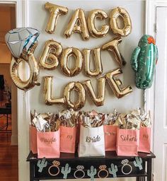 taco bout love balloons are on display in front of a table filled with bags