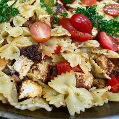 a close up of a plate of food with pasta and vegetables on it, including tomatoes