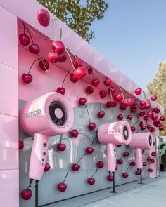 pink hair dryers on display in front of a wall with cherries hanging from it