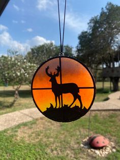 a stained glass ornament depicting a deer and antelope in the sunset