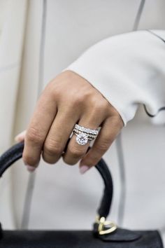 a close up of a person holding a handbag with a ring on it's finger