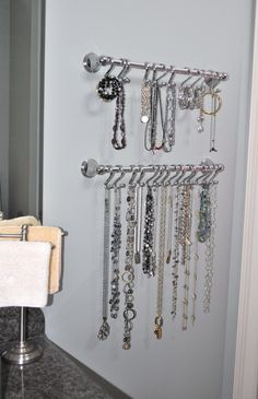 a bunch of necklaces are hanging on the wall next to a sink and mirror