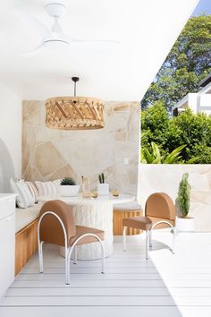 an outdoor kitchen and dining area with white walls, wood flooring and ceiling fan