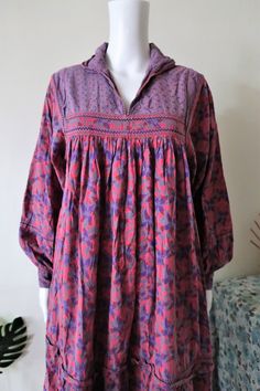 Amazing True Vintage Indian folklore midi dress from the 1980s. Made from a comfortable cotton fabric with a stunning floral pattern. A-line cut. Bib front and yoke, split neck (the collar can be worn up or down). Vest effect, wide sleeves with buttoned cuffs, two side pockets, ruffle hem. Unlined. ERA: 1980s BRAND: El Saad Copenhagen COLOUR: Puple/lilac, pink, grey, brown FABRIC: 100% cotton SIZE: Vintage size S - please check the measurements below for reference MEASUREMENTS: Pit to pit 45cm, Folk Dresses With Woven Motifs And Long Sleeves, Bohemian Prairie Dress With Floral Print In Cotton, Multicolor Folk Dress With Boho Print, Cottagecore Long Sleeve Vintage Dress With Floral Print, Pink Long Sleeve Folk Dress, Vintage Long Sleeve Smock Dress, Multicolor Long Sleeve Folk Dress, Vintage Long-sleeved Smock Dress, Embroidered Folk Boho Dress With V-neck