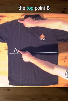 a person pointing at a black shirt with the top point b on it