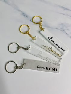 three keychains with tags attached to them sitting on a marble counter top next to each other