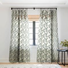 a living room with white walls and floral curtains on the windowsill, along with a rug