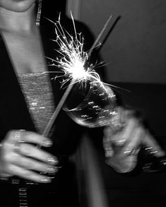 a woman holding a wine glass with sparklers in it