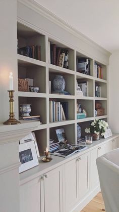 a living room filled with lots of white furniture and bookshelves next to a window