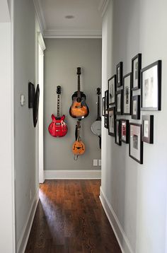 a hallway with guitars hanging on the wall and pictures on the wall behind it,