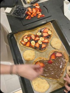 someone is making heart shaped pastries with chocolate and strawberries on the cookie sheet