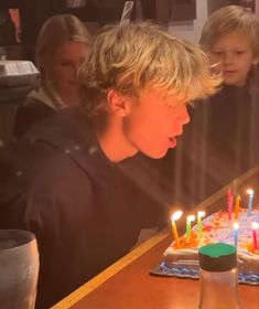 a young boy blowing out candles on his birthday cake