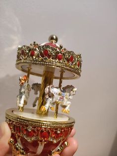 there is a miniature carousel with figurines on it in someone's hand