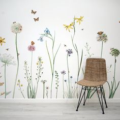 a chair in front of a wall with flowers and butterflies painted on the walls behind it