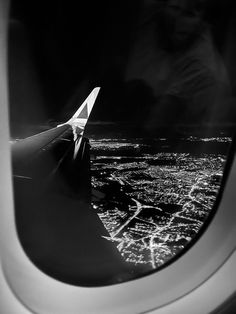 an airplane wing is seen through the window at night, with city lights in the background