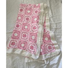 two pink and white crocheted afghans sitting on top of a bed next to each other