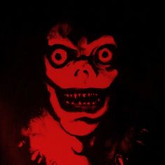 an evil looking clown with big eyes and fangs on it's face in the dark