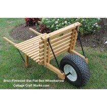 a wooden wheelbarrow sitting in the grass near some flowers and bushes with wheels attached to it