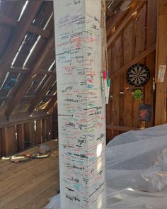 a tall white pole covered in lots of writing on it's side next to a dart