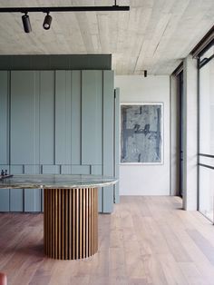 an empty room with wooden floors and gray walls, has a round table in the center