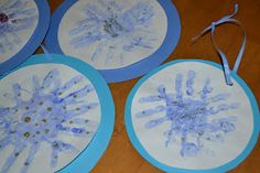 four handprinted snowflakes are hanging on a table with blue trim around them