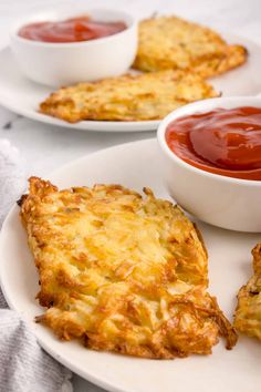 two white plates topped with cheesy hash browns and ketchup on the side