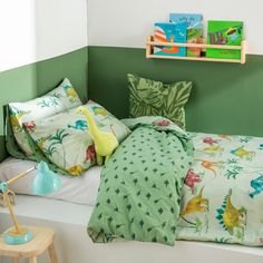 a child's bed with dinosaur sheets and pillows