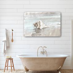 a bath tub sitting under a painting on the wall next to a wooden stool and shelf