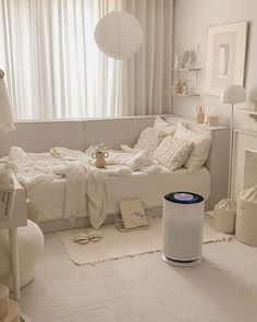 a white bedroom with a bed, table and other items on the floor in front of a window