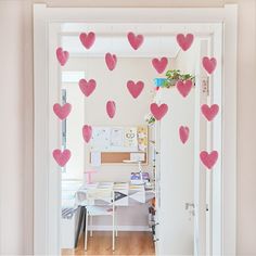 pink hearts are hanging from the ceiling above a desk in an office space with white walls