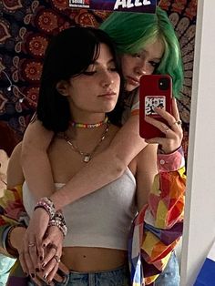 two young women taking a selfie in front of a mirror with their cell phones