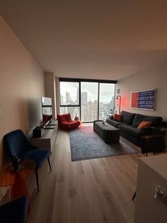 a living room filled with furniture and a large window overlooking the cityscape in the distance