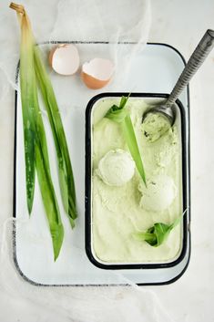 an ice cream dish with green onions and two eggs on the side next to it