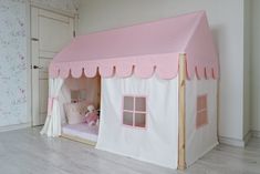 a pink and white tent bed with curtains on the top is next to a door